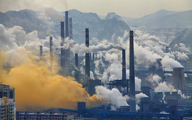 Industrial landscape with cooling towers belching smoke and mountainous landscape in the background