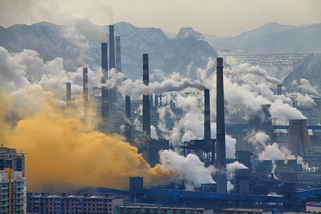 Industrial landscape with cooling towers belching smoke and mountainous landscape in the background