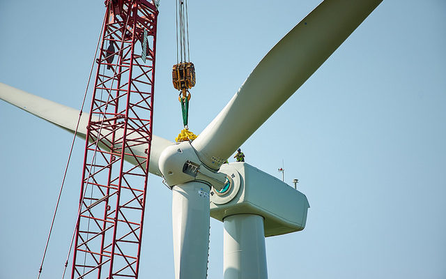 A crane winching something onto a wind turbine