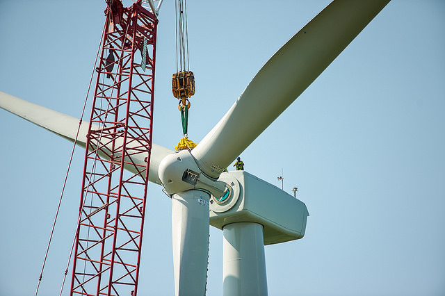 A crane winching something onto a wind turbine