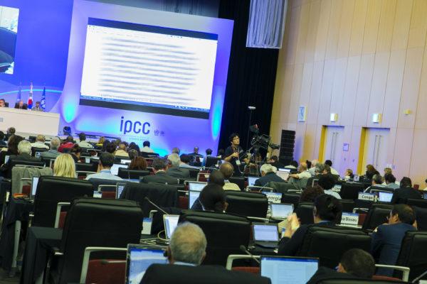 A conference auditorium with rows of people sat in front of captop monitors