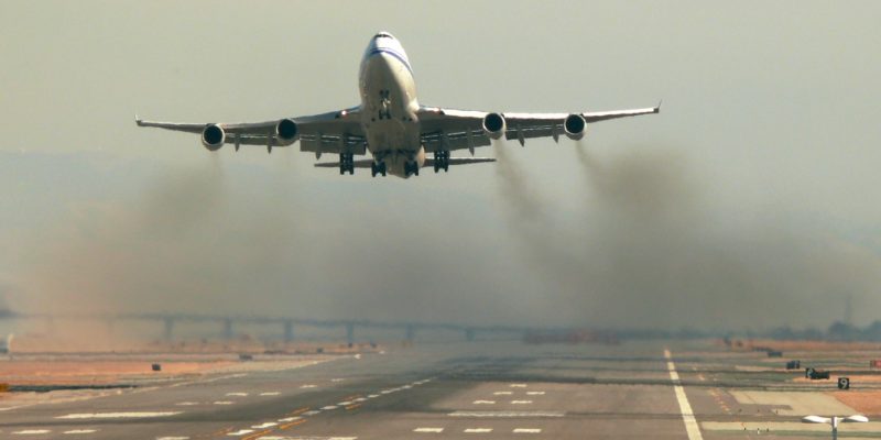 Aeroplane taking off from a runway with black smoke coming from the engines