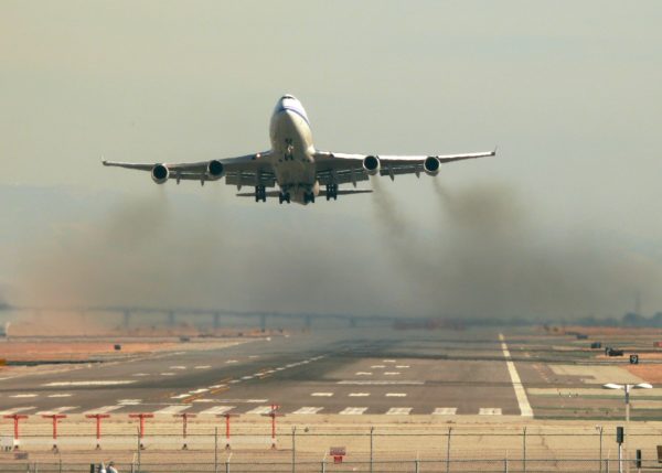 Aeroplane taking off from a runway with black smoke coming from the engines