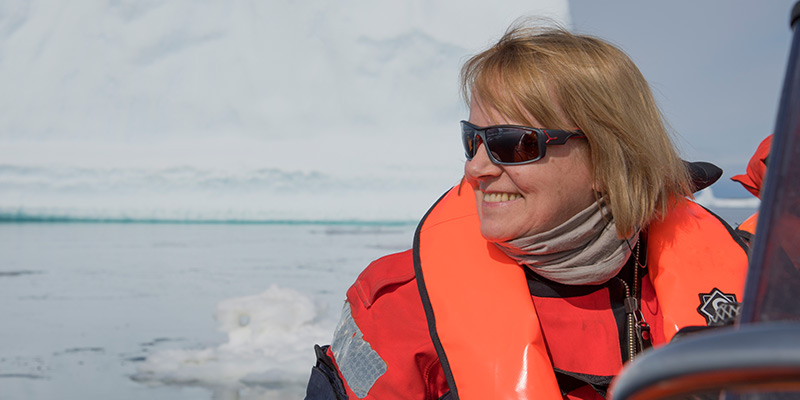 Professor Dame Jane Francis wearing sunglasses and a life-jacket on a boat at sea