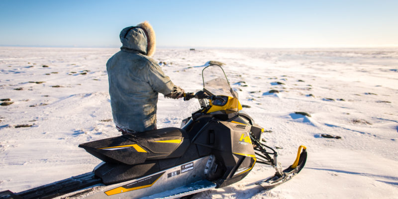 Person dressed warmly standing on a snow ski against a snowy landscape on a clear day
