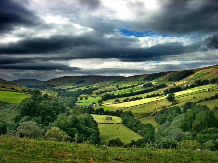 Rolling scenic landscape showing fields and boundaries on a heavily clouded day