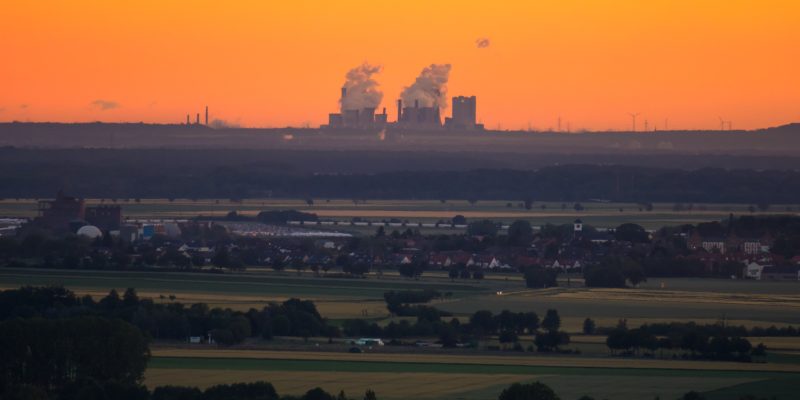Skyline view of a power plant at dusk, with orange sky