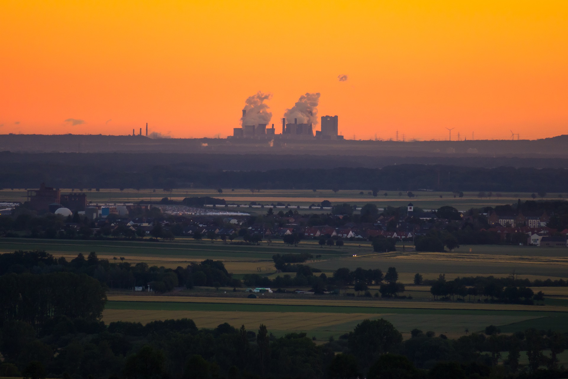 Skyline view of a power plant at dusk, with orange sky