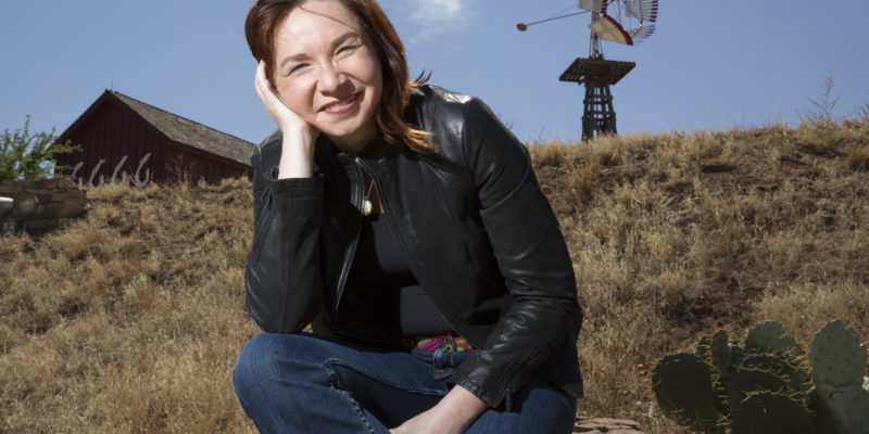 Outside shot of Dr Katharine Hayhoe, sitting on a rock on a cloudless day