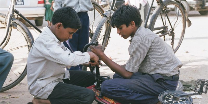 Two young boys repairing a bicycle