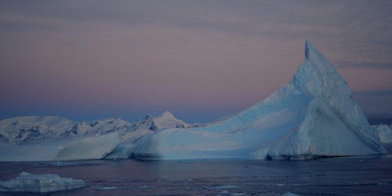 An iceberg in the Amundsen Sea Embayment. In the background, the sky is shades of pink.
