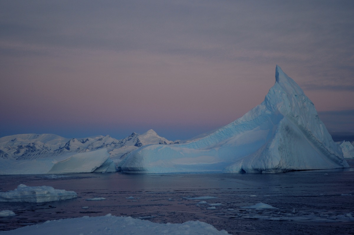 An iceberg in the Amundsen Sea Embayment. In the background, the sky is shades of pink.