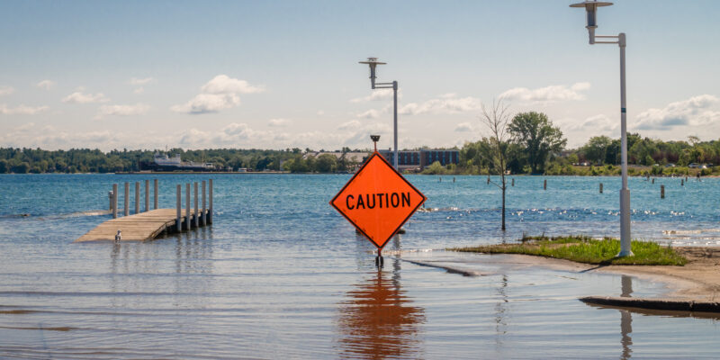 An orange 'CAUTION' sign in flood water
